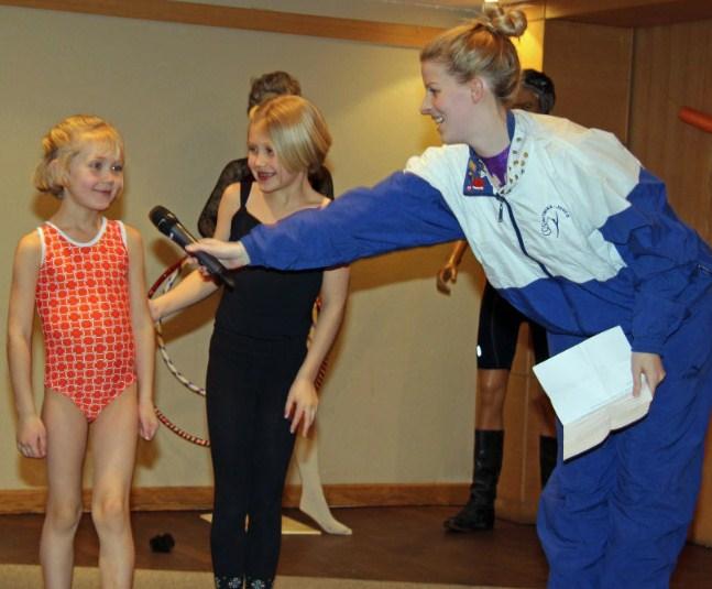 Amicitia's "esinaine" and former gymnast Kristina Põldre pursuading mini-gymnasts Imbi and Eila Uukkivi to demonstrate a few of their favourite gymnastics moves at Küünlapäev. - pics/2015/03/44526_002.jpg