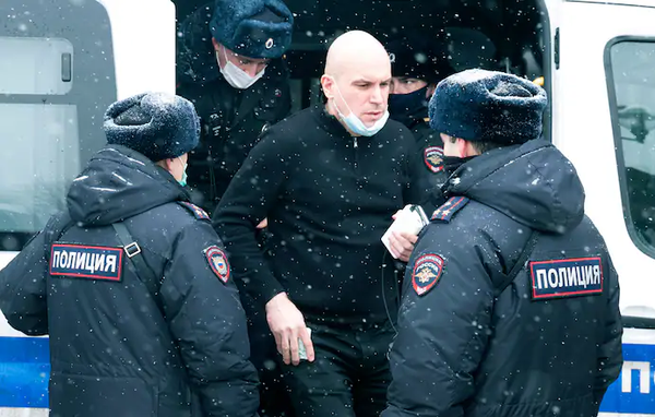 A man stands near a police bus after he was detained in Moscow on March 13, along with nearly 200 participants of a forum of independent members of municipal councils. (Victor Berezkin/AP) - pics/2021/04/58177_001.webp