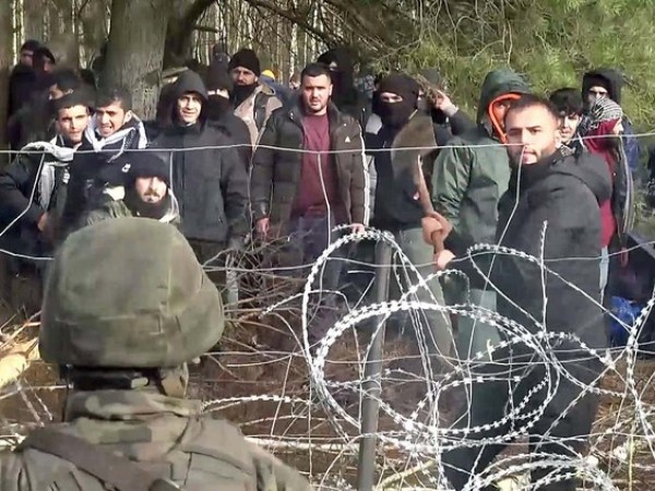 A still image, taken from a handout video released by the Polish Defence Ministry, shows a Polish service member defending a barbed wire fence as hundreds of migrants gather on the Belarusian side of the border with Poland in an attempt to cross, near Kuznica Bialostocka, Poland, November 8, 2021. PHOTO BY MON/HANDOUT VIA REUTERS - pics/2021/11/58730_001_t.jpg