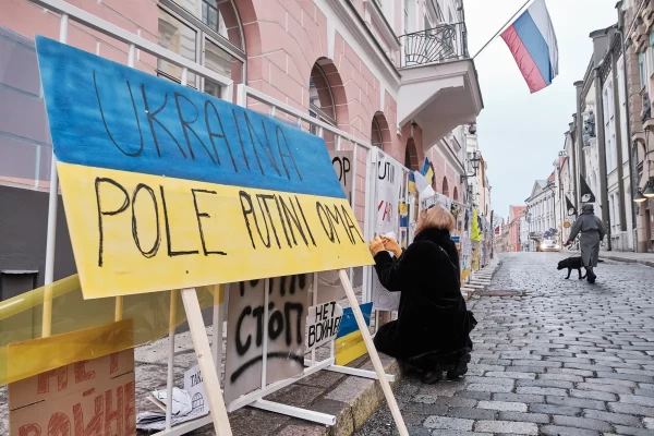 Laura Juristo makes some repairs to the display of Ukrainian flags and antiwar signs outside Russia's embassy in Tallinn, capital of Estonia. PHOTOGRAPHY BY HENDRIK OSULA/THE GLOBE AND MAIL - pics/2022/03/59063_001_t.webp